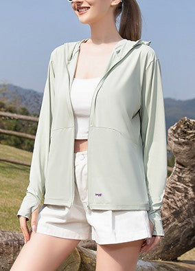 Woman wearing a green sun protection jacket with a hood, standing outdoors.