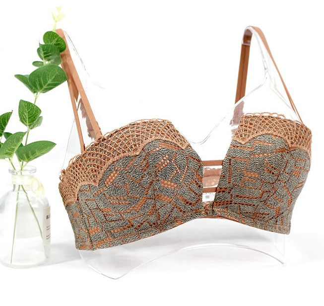 Front view of a vintage push-up bra with lace details and adjustable straps, displayed with greenery in the background.