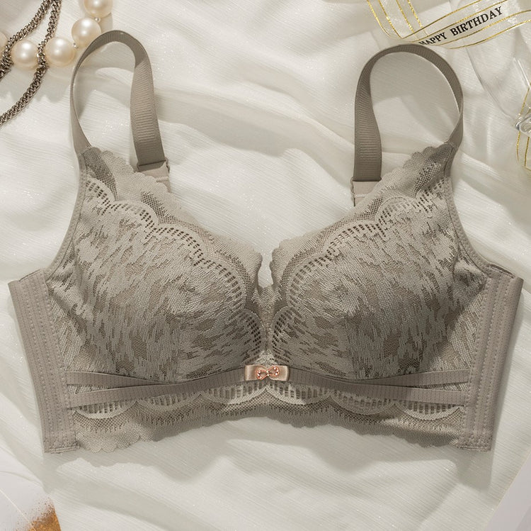 Flat lay of a green Chic Lace Wireless Push-up Bra, highlighting the elegant lace design and center bow detail, displayed on a light fabric background with decorative pearls.